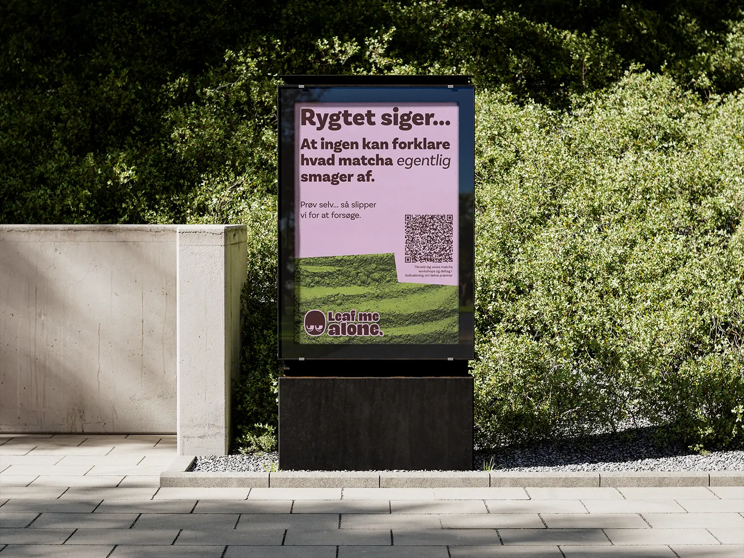 Mockup of the poster on display in the streets, in front of some greenery